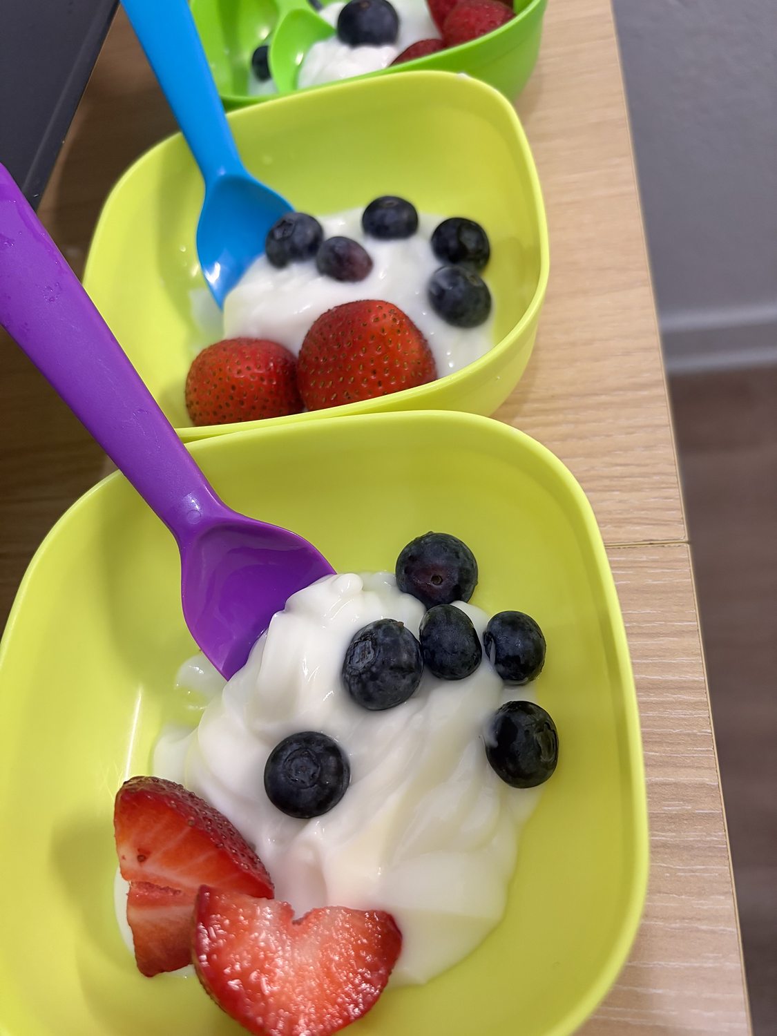 Yogurt with strawberries and blueberries in green bowls